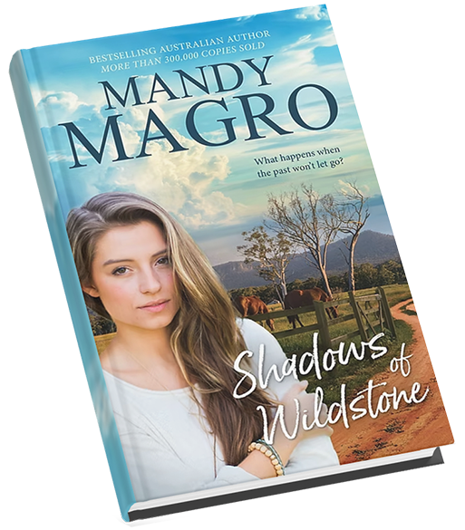 Cover of "Shadows of Wildstone" by Mandy Magro, featuring a woman with long hair and a countryside background.